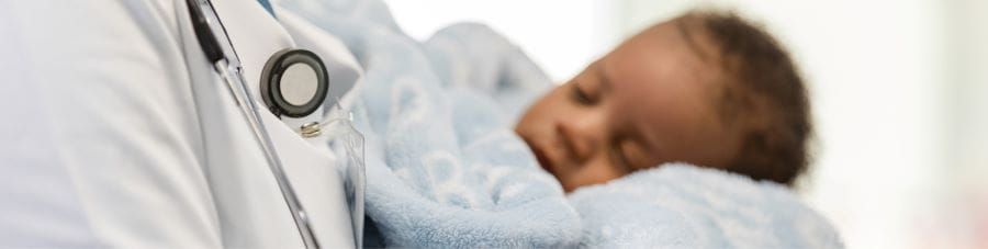 Doctor holds an infant wrapped in a blanket.