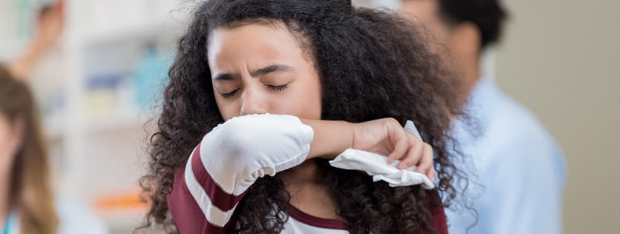 Young girl coughing in classroom.