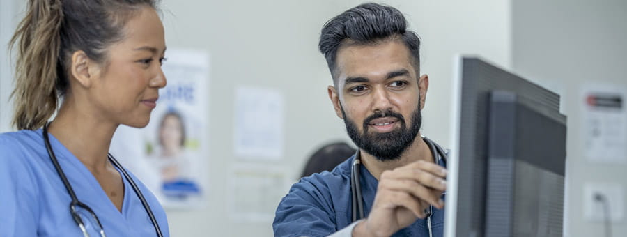Hospital colleagues look at something on the computer monitor.