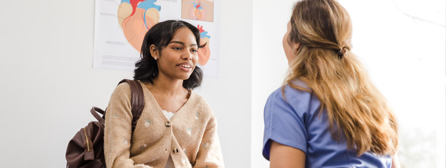 Doctor and teen talk in exam room.