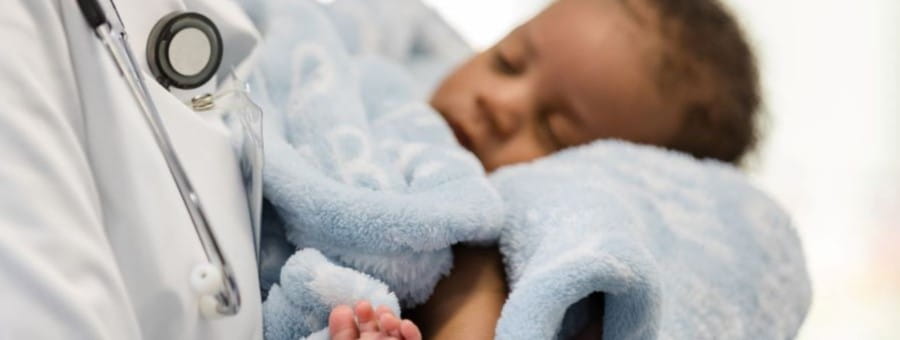 Doctor holds an infant wrapped in a blanket.