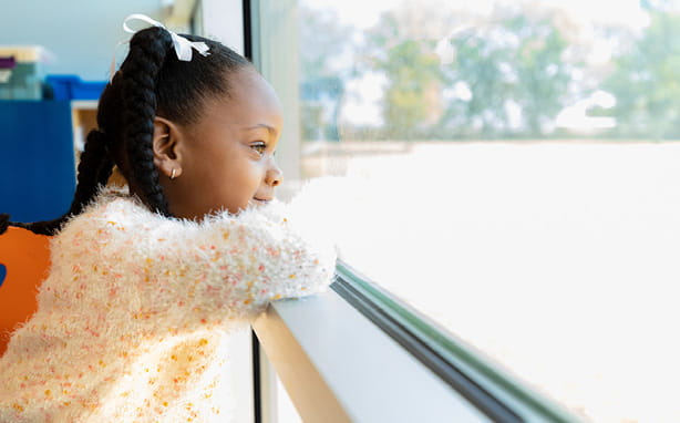 A young girl looks out a window.
