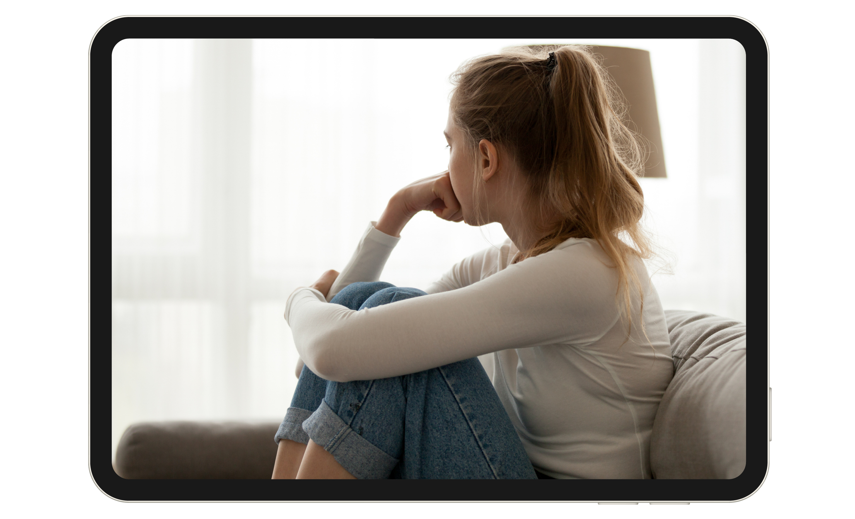 A young girl sitting on a couch, looking out the window.