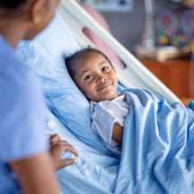 Child in hospital bed receiving therapy treatment.